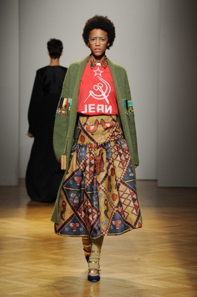 Stella Jean, Winter 2017 Ethno Look von Stella Jean. Weiter langer Rock. Roter Pullover und grüne Strickjacke.