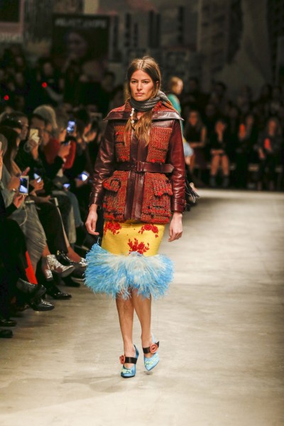 Prada, Winter 2017 Patchworklook von Prada. Jacke mit Lederarmen und Strickvorderteil. Gelber Rock mit blauen Federbesatz.