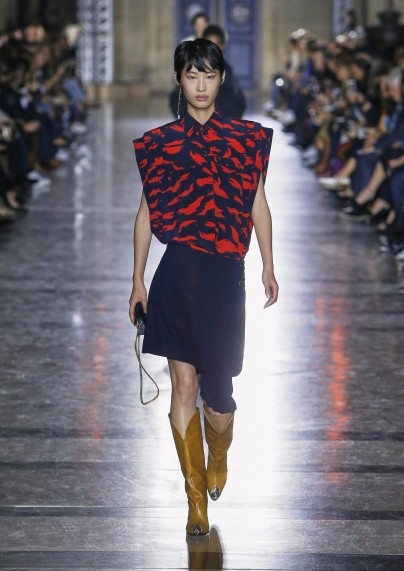 Modenschau Givenchy Sommer 2018. Asiatisches Model mit asymmetrischem Rock und ärmelloser Bluse mit blau-rotem Muster.