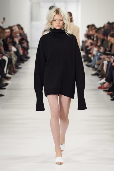 Foto: Maison Margiela Blondes Model in schwarzem oversized Pullover mit Rollkragen und überlangen Armen von Maison Margiela.