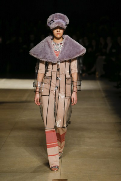 Foto: Miu Miu Transparenter Mantel mit violettem Pelzkragen von Miu Miu. Model trägt violette Mütze aus Pelz.