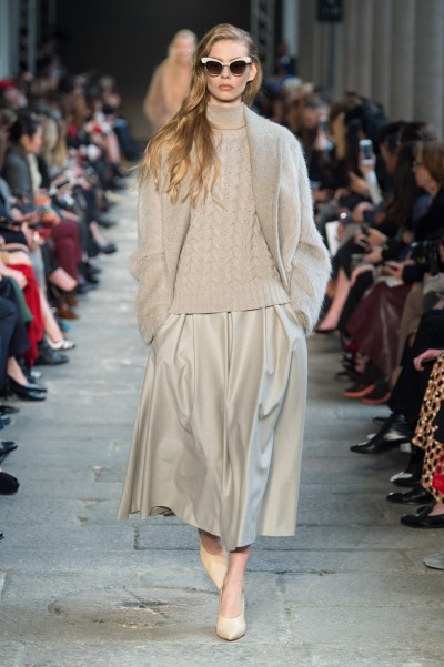 Foto: Max Mara Blondes Model. Max Mara Modenschau. Cremefarbener Look. Rollkragenpullover mit Zopfmuster, langer Faltenrock. Strickjacke.