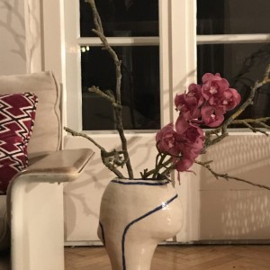 © Nikolas Feireiss Violetter Orchideen Stiel mit üppigen Blüten in avantgardistischer Keramikvase. Sessel von Dieter Rams im Anschnitt.