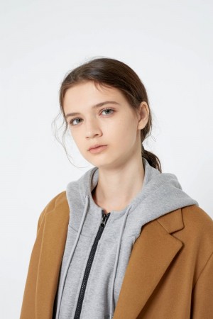 Mädchen in beigefarbenen oversized Mantel und grauem Hoodie