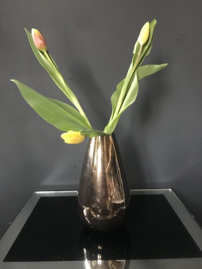 Foto/Styling: Nikolas Feireiss Drei gelbe Tulpen in goldener spiegelnder Vase.