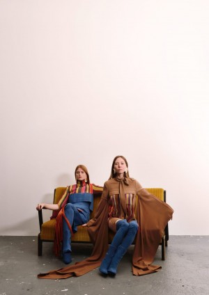 Modeschule. Zwei Models sitzen auf einem Sofa. Jeanslook , dazu buntgestreifte Oberteile