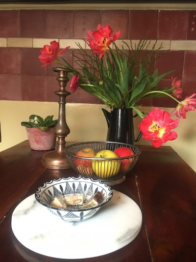 Foto/Styling: Nikolas Feireiss Rote aufgeblühte Tulpen auf Bauerntisch. Äpfel, Kerzenständer. Kleine schwarz weiße Schale.