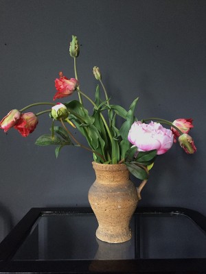 Foto/Styling: Nikolas Feireiss Rote Papageientulpen und Pfingstrose in bäuerlichem Krug vor schwarzem Hintergrund.