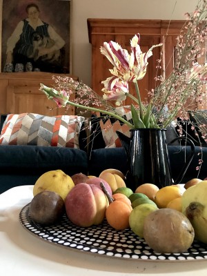 Foto/Styling: Nikolas Feireiss Aufgeblühte rot-weisse Papageientulpen in schwarzer Kanne. Früchte aus gepunktetem Tablett. Im Im Hintergrund Bauernschränke, Porträtbild.