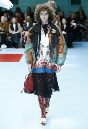 Foto: Gucci Herbst Winter 2018/19 Gucci Schau Herbst/Winter 2018/19. Model mit oversized Jacke, Spitzenrock und weiter Bluse mit Blumendruck.