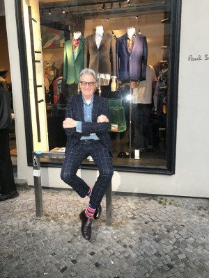 Paul Smith in Berlin sitzend vor seinem Geschäft.